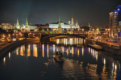 Illuminated bridge over river in city at night.