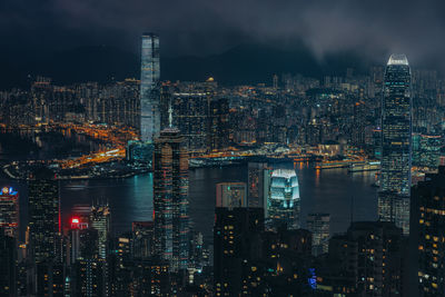 Illuminated modern buildings in city against sky at night