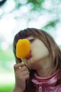 Low angle portrait of cute girl eating orange ice lolly