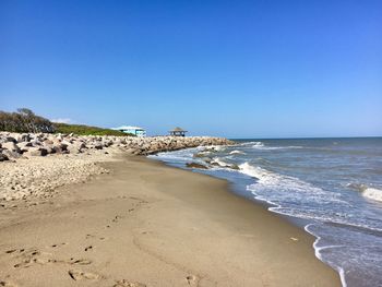 Scenic view of beach against clear blue sky