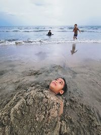 Children on beach against sky