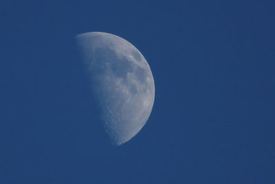 Low angle view of half moon against blue sky