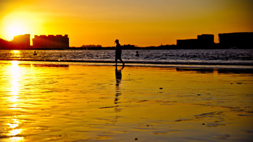 Silhouette man standing on beach against sky during sunset