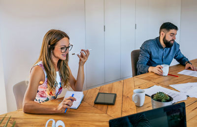 Young woman using phone while sitting on table