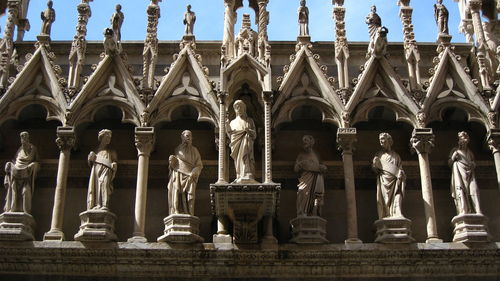 Low angle view of statues on building against sky