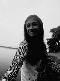 Portrait of smiling young woman standing against tree