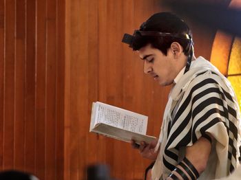 Side view of young man reading book