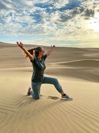 Full length of happy young woman on sand dune