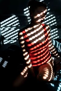 Young woman looking away while sitting in darkroom