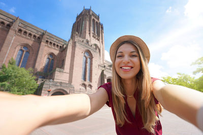 Beautiful young woman taking selfie photo in front of liverpool cathedral in england, uk