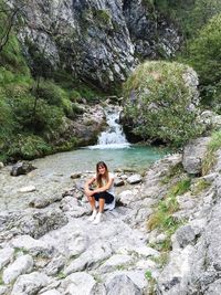 Portrait of woman sitting on rock in forest