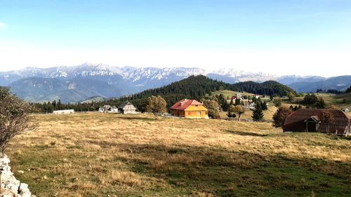 Houses on field by mountains against sky