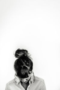 Woman with hair bun looking down against white background