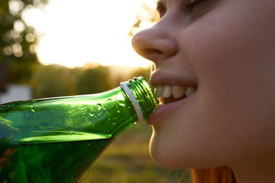 Close-up portrait of young woman drinking water from bottle