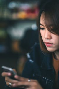 Woman using phone while sitting by table in cafe