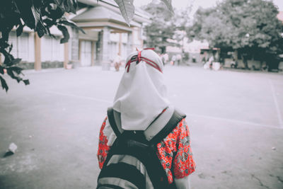 Rear view of woman standing on street in city