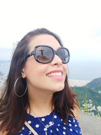 Portrait of smiling young woman against sky