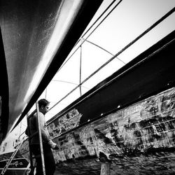 Side view of man standing on bridge over canal in city