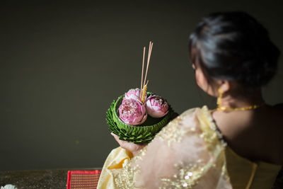 Side view of woman holding wedding dress against black background