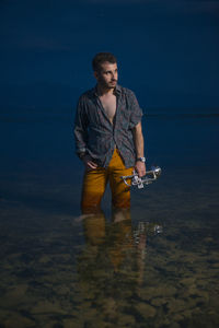 Young man looking away while standing in sea