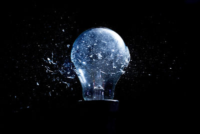 Close-up of illuminated light bulb against black background