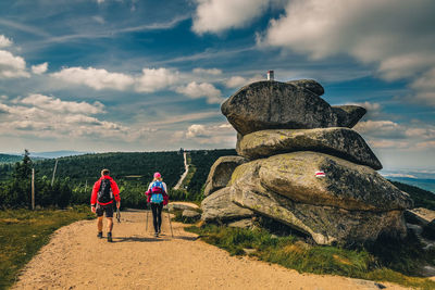 Rear view of people on rock against sky