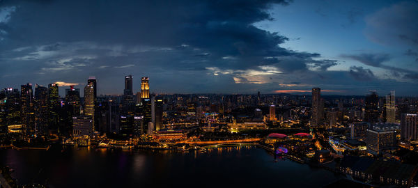 Illuminated buildings in city against sky at dusk