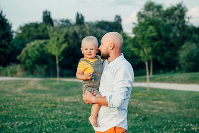 Father standing with son against plants at park