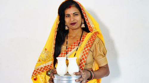 Portrait of young woman holding gift against white background