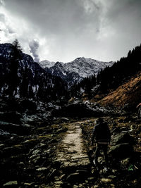 Rear view of man standing on mountain against sky