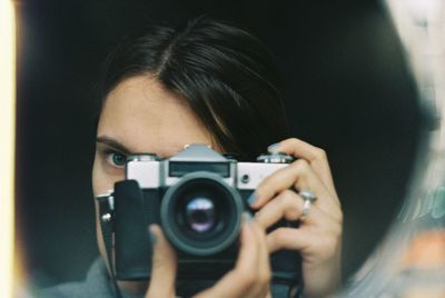 Reflection of woman photographing with camera on mirror