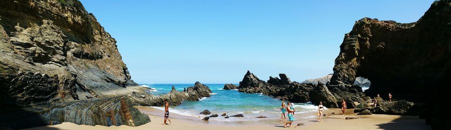 People on beach against clear blue sky