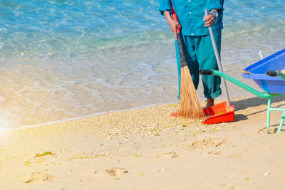 Low section of man cleaning beach