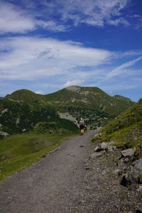 People walking on road by mountain against sky