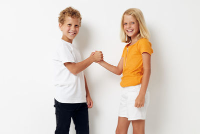 Sibling holding hands against white background