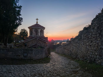 Footpath amidst buildings against sky during sunset