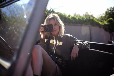 Portrait of woman photographing through camera while sitting in car