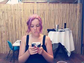 Woman using smart phone while sitting on restaurant