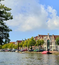 Scenic view of river by buildings against sky