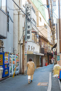 Rear view of man walking on street in city