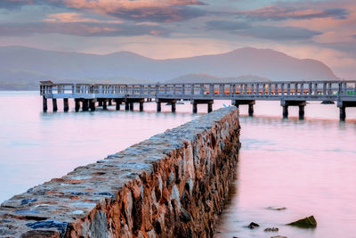 Pier over sea against sky during sunset