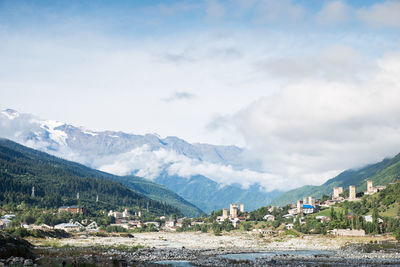 Scenic view of town by mountains against sky