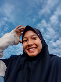 Portrait of a smiling young woman against sky