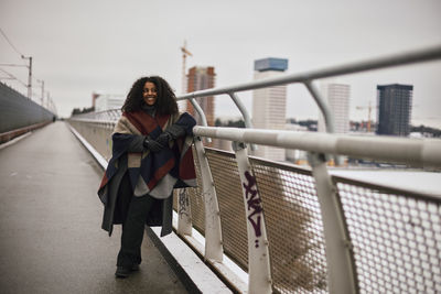 Smiling woman standing on footbridge