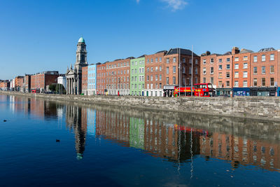 Reflection of buildings in water against clear blue sky