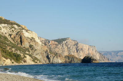 Scenic view of sea and mountains against clear sky