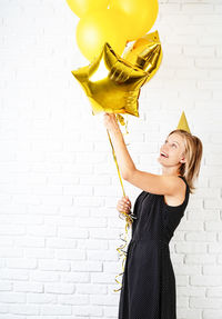 Young woman with umbrella standing against wall