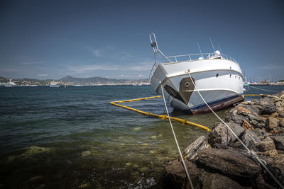 Sailboat moored on sea shore against sky