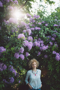 Portrait of smiling mid adult woman standing against purple flowering plants