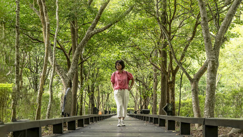 Woman standing by railing against trees